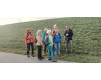 Wandergruppe steht auf Feldweg in Nebel, Österreich, mit Blick auf grüne Hügel.